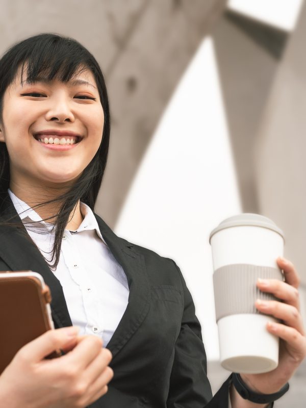 Business Asian woman holding laptop and coffee cup outdoor